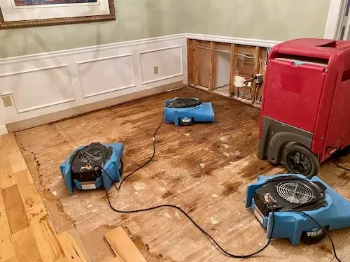Air movers and a dehumidifier drying a dining room with the floor pulled up in a Smyrna home