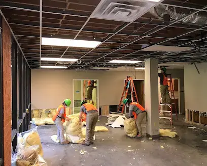 Crew removing wet ceiling insulation and debris inside a commercial space
