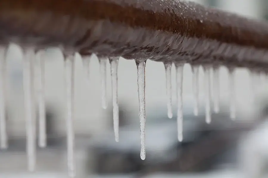 Icicles hanging from a frozen pipe during a hard freeze